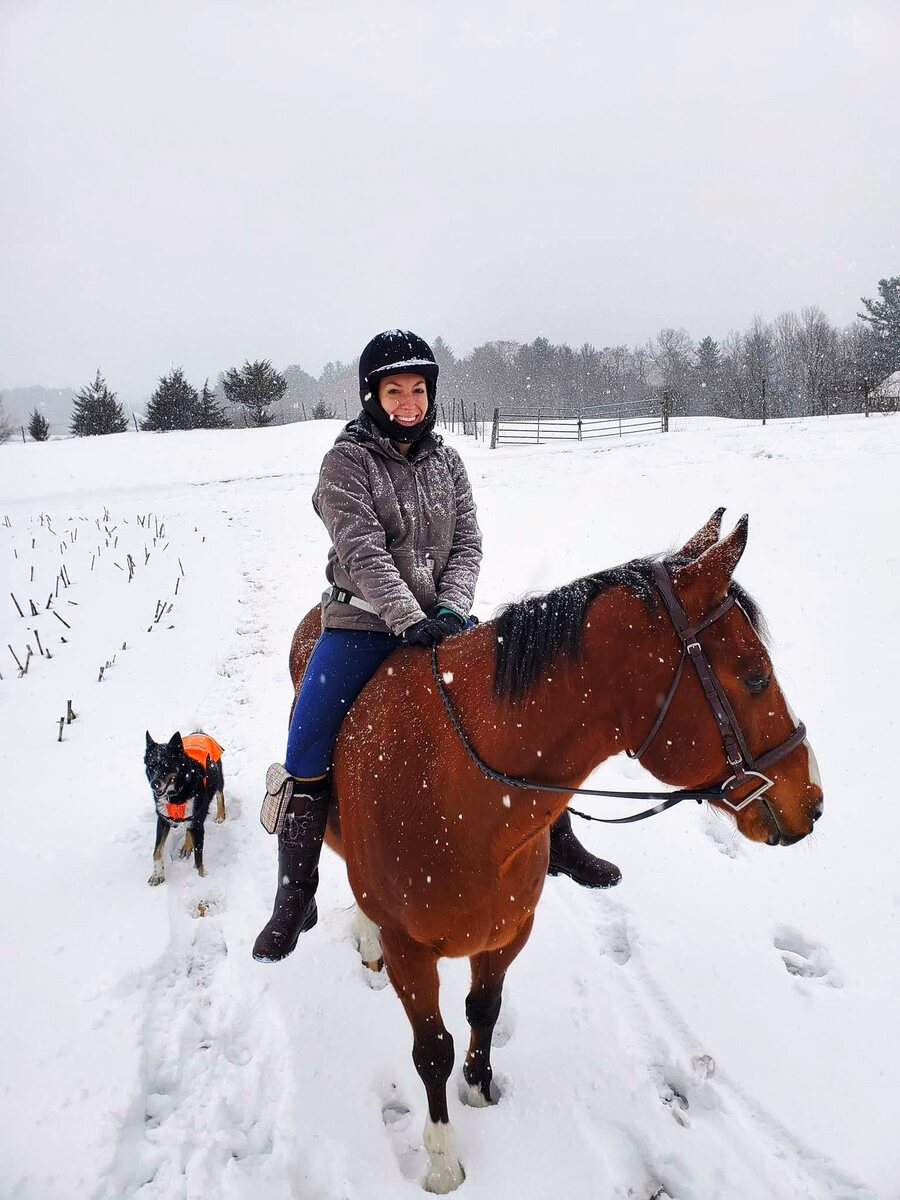 Anna on horseback in the snow with her dog