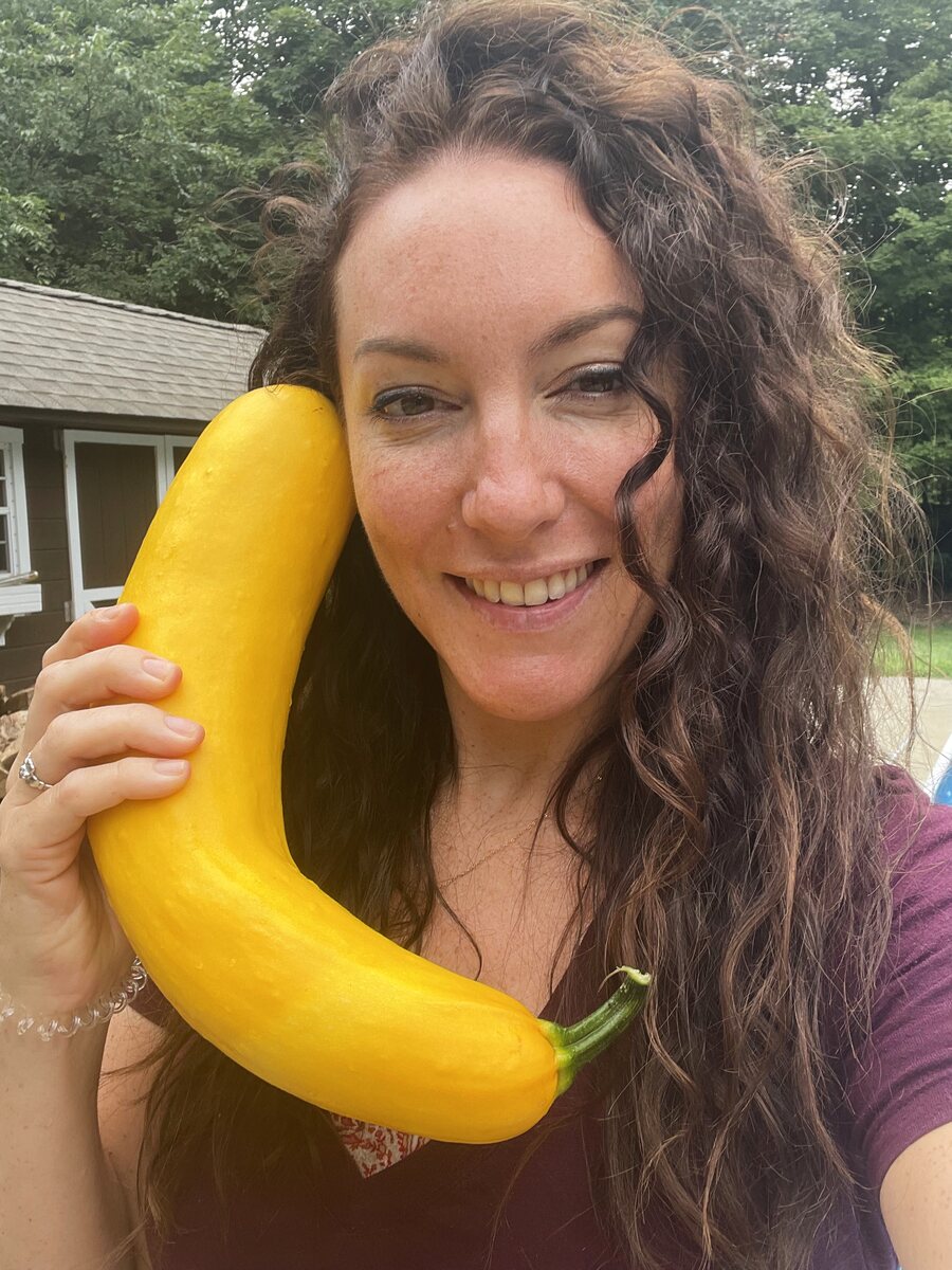 Anna smiling, holding a freshly picked yellow squash